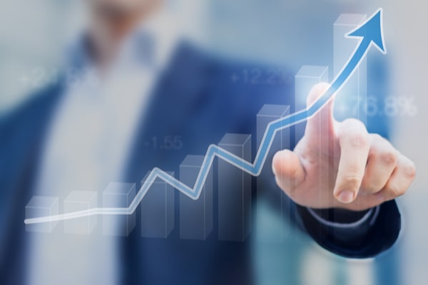 man in suit points to increasing graph with trendline