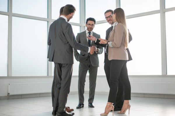 5 people in suits stand in a circle and discuss
