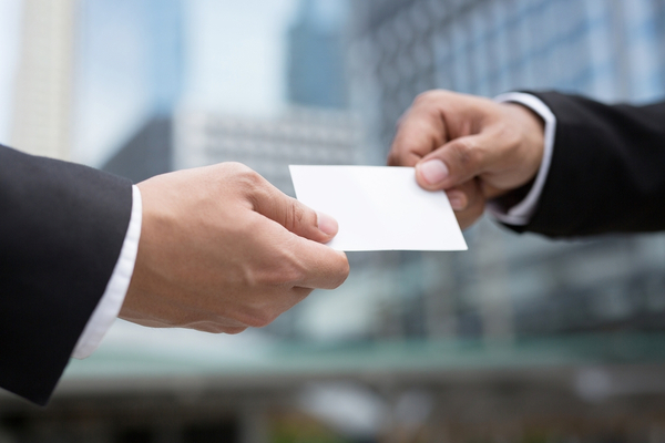 two people in suits hand each other a business card