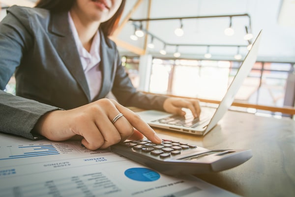woman in suit sitting at desk with laptop and calculator