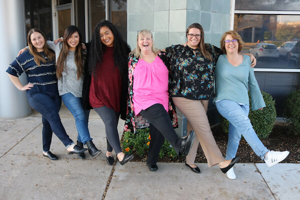 6 women with arms around each other smiling