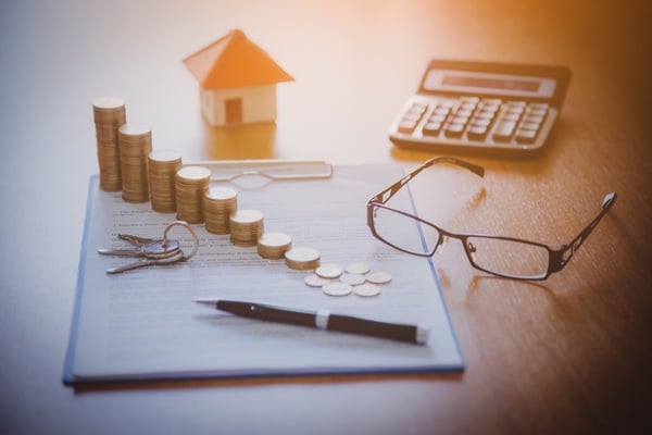 table with papers, glasses, calculator, stacked coins and keys
