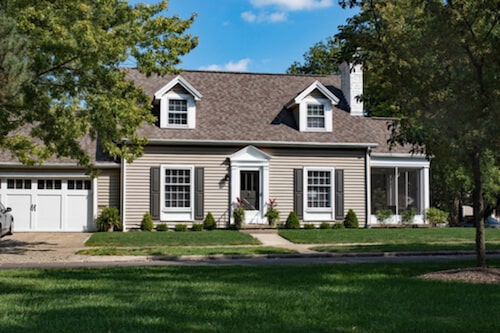 a tan house with a garage and small lawn