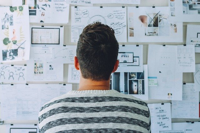 man looking at board of diagrams and design ideas