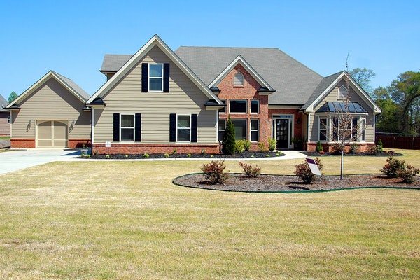brick and tan house with a lawn