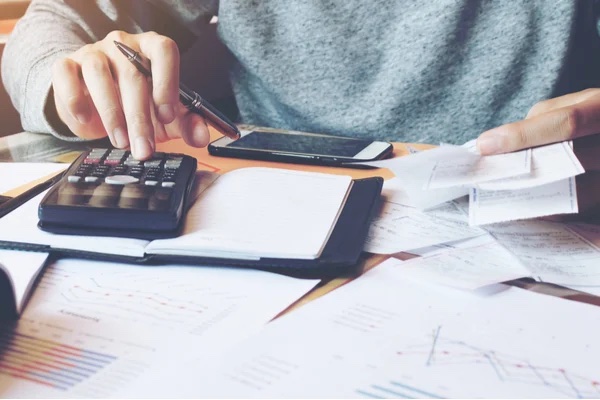 person going through papers with a pen and calculator